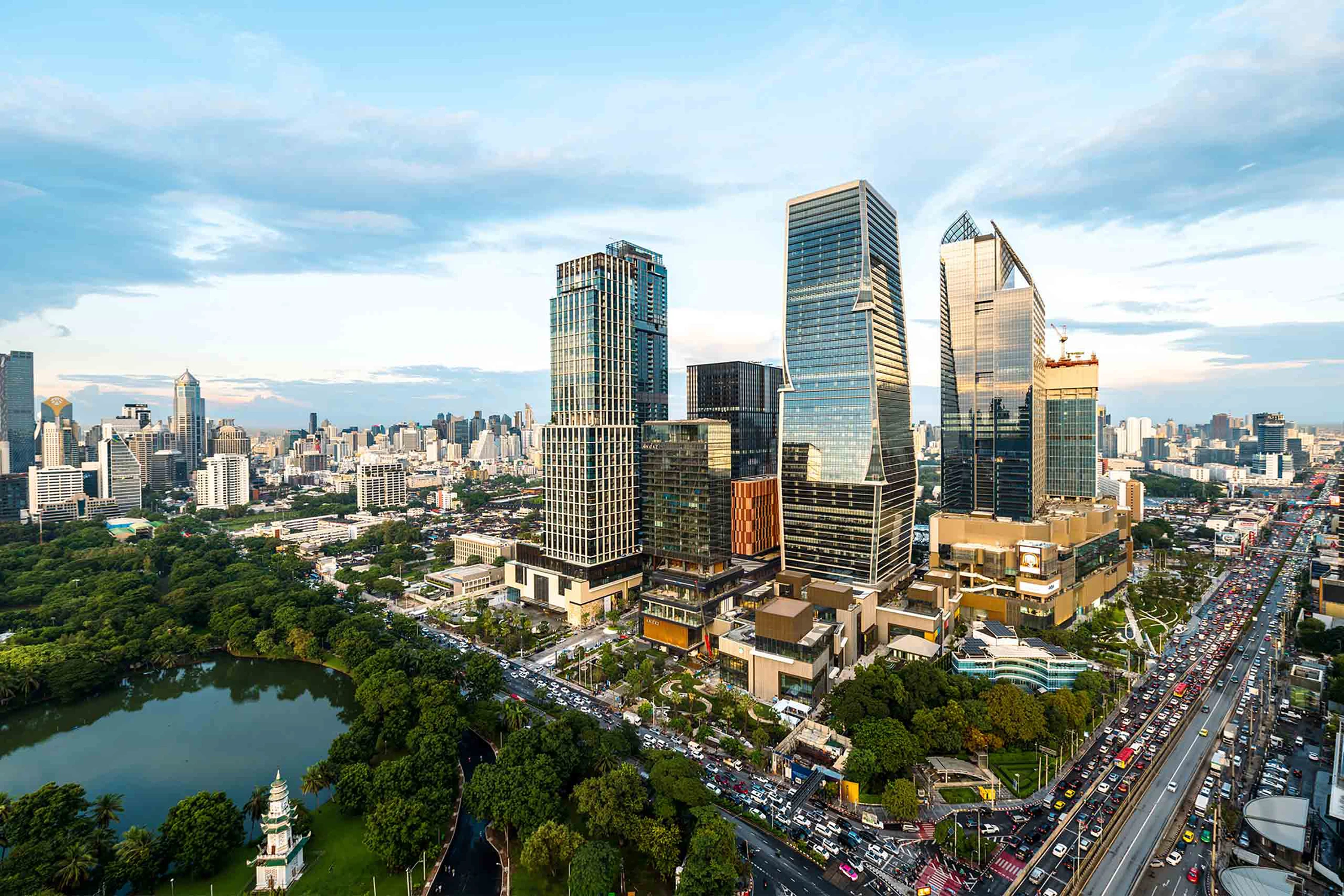 Современные стеклянные офисные здания и жилые комплексы рядом с зеленым парком Лумпини и оживленным шоссе в Бангкоке